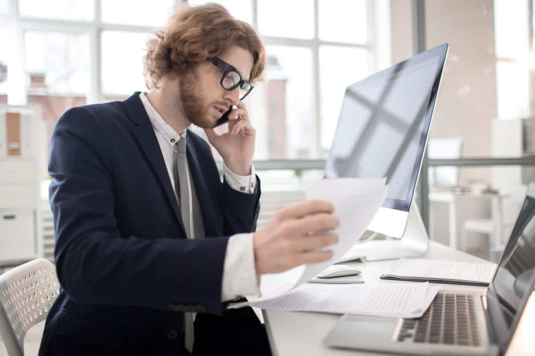 man looking at papers on the phone at his desk
